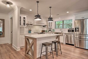 A modern kitchen with a large island, stainless steel appliances, and pendant lighting.