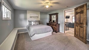 A bedroom with a bed, a dresser, a ceiling fan, and a door leading to a bathroom. - Rome City Waterfront Oasis w/ Beach & Dock! (Rome City)