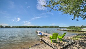 A wooden dock extending into a calm lake, with two green chairs and a small boat moored at the end. - Rome City Waterfront Oasis w/ Beach & Dock! (Rome City)
