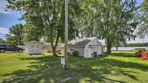 A residential property with a garage, a lawn, and a lake view. - Rome City Waterfront Oasis w/ Beach & Dock! (Rome City)