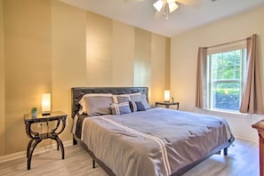 A bedroom with a large bed, two bedside tables, a window with curtains, and a ceiling fan. - Porch & Community Perks: Walkable Lewes Condo (Lewes)
