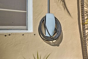 Eine Tesla-Ladestation, angebracht an einer beigen Wand, mit einem Fenster zur Linke.