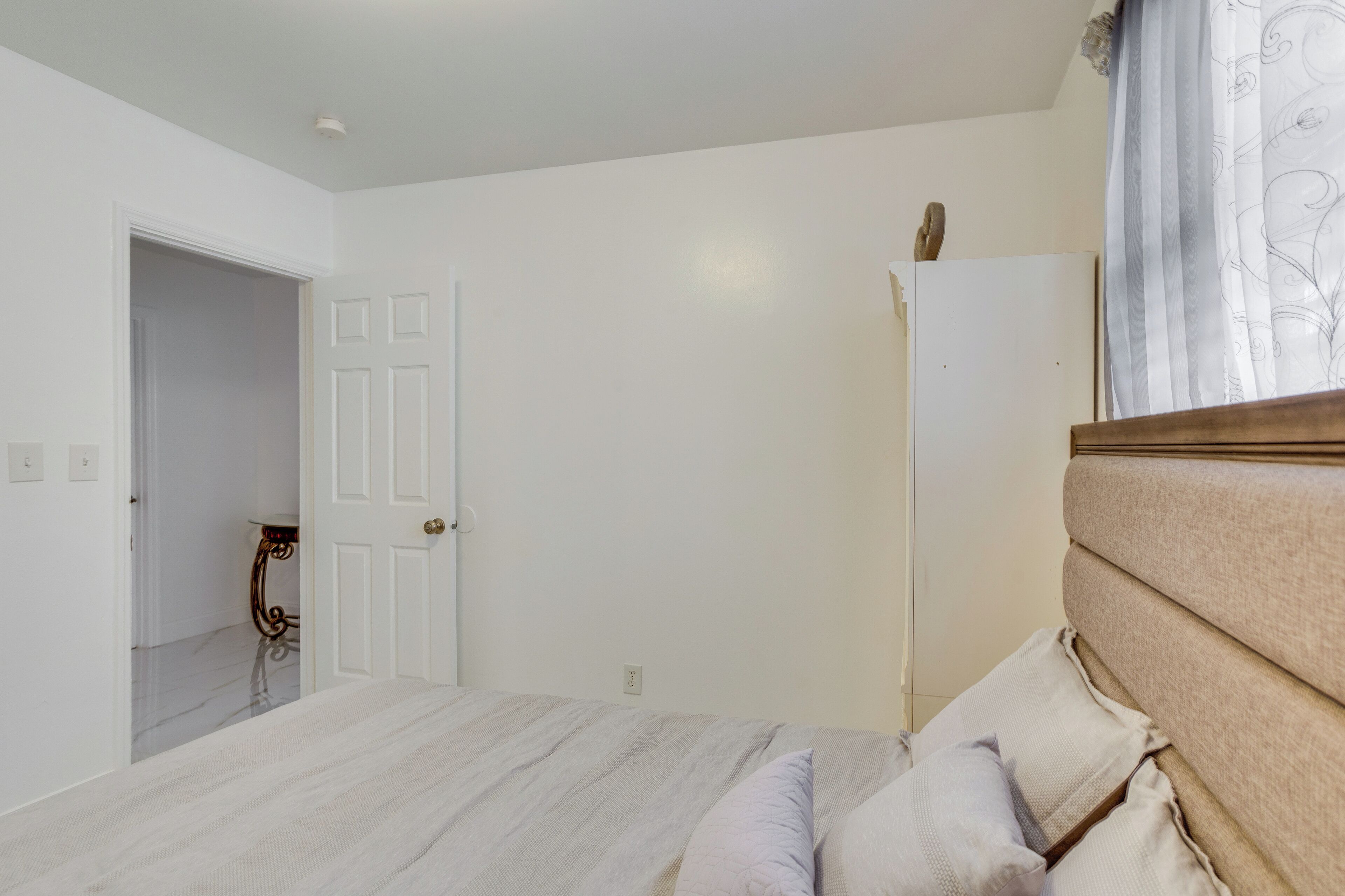 Une chambre à coucher avec un lit, une porte et une petite table.