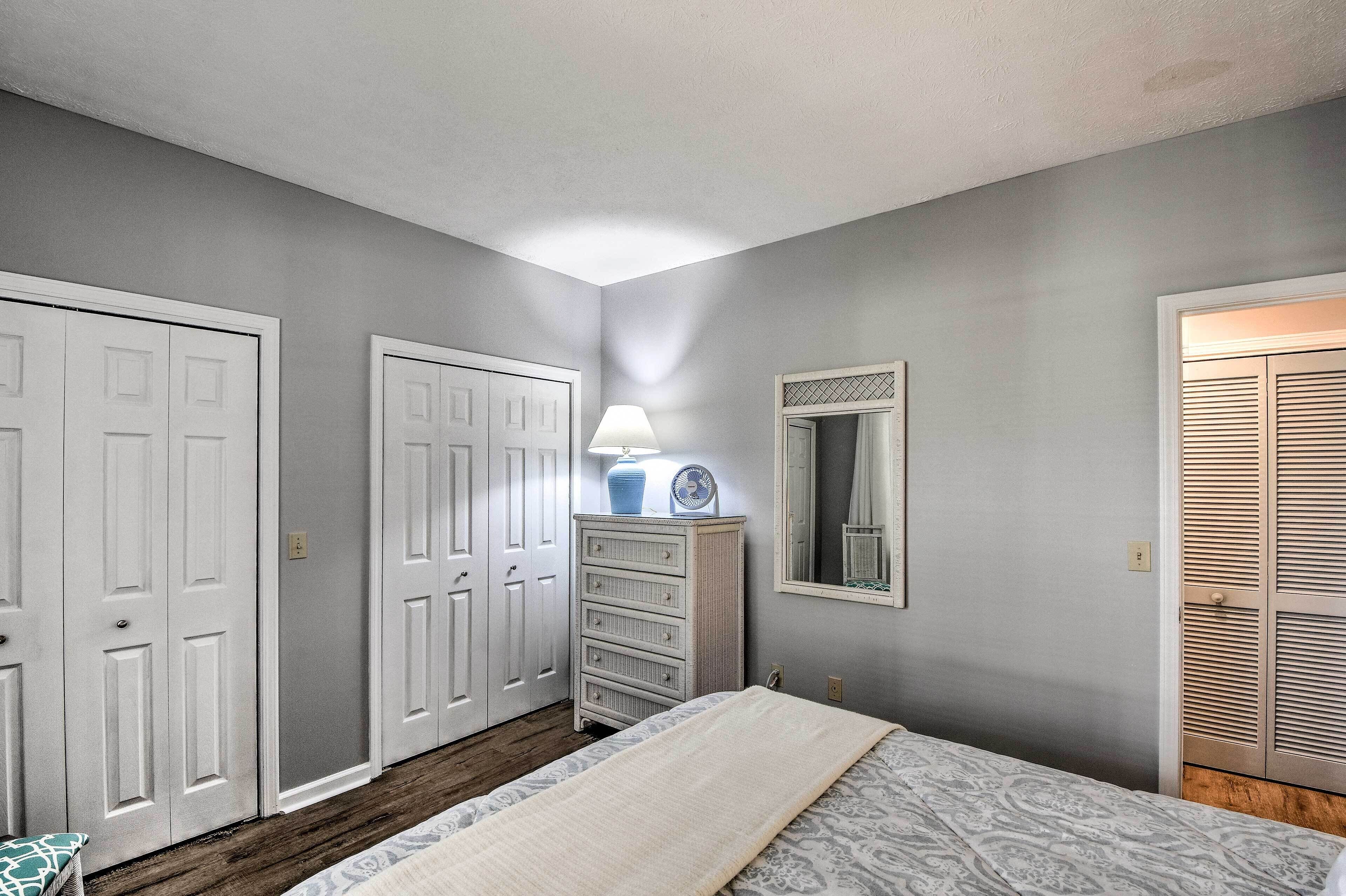 A bedroom with a bed, dresser, and two doors.