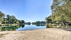 A sandy beach with a calm lake surrounded by trees. - Views, Pools & Marina: Lake Keowee Condo! (Salem)