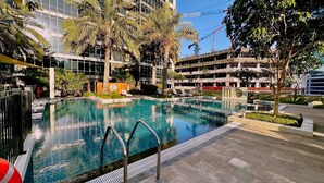 Un hotel modern amb piscina, palmeres i un edifici de diversos pisos al fons.