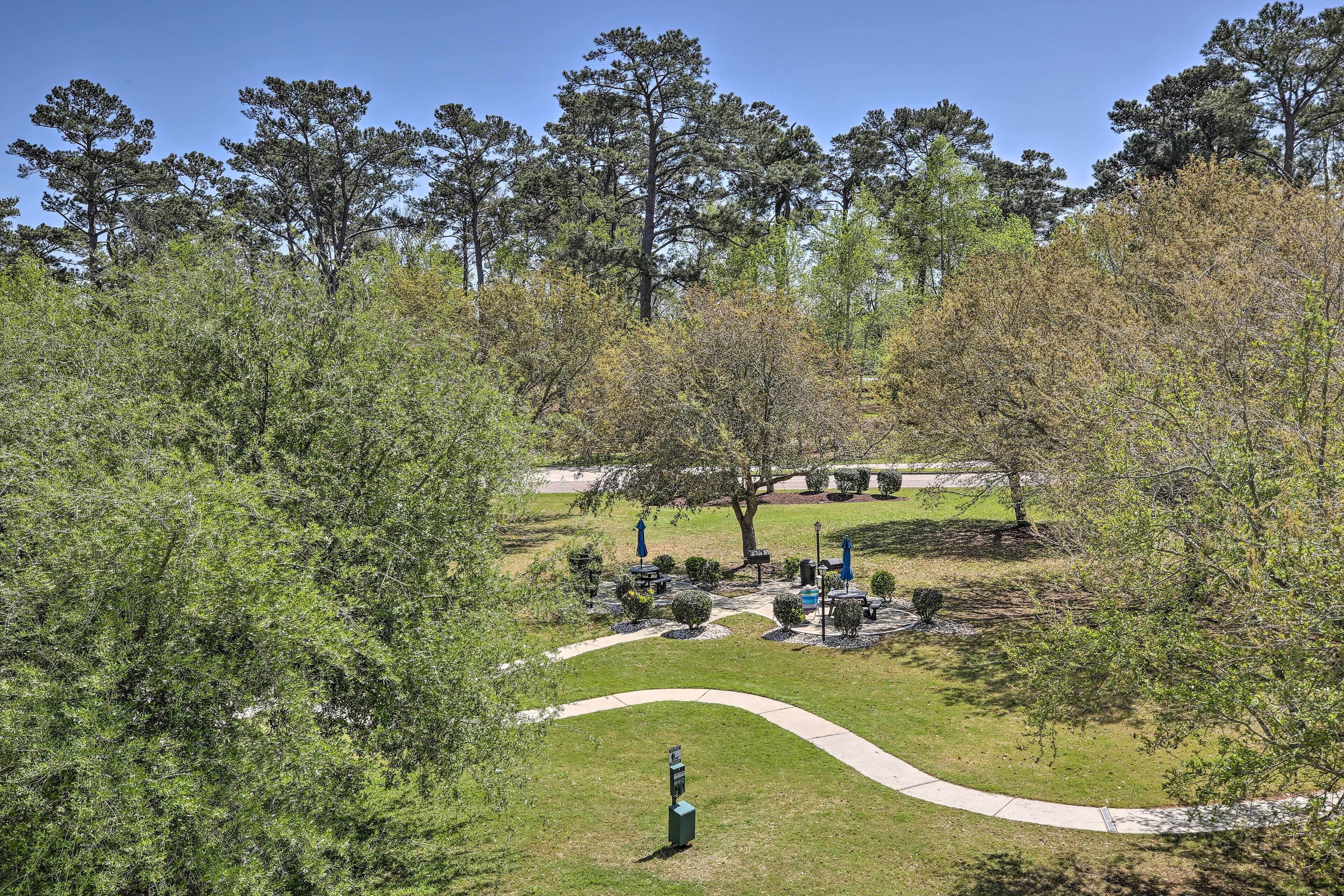 A park with a winding path, picnic tables, and a small kiosk.