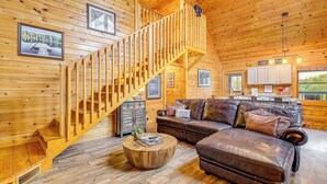 A wooden cabin interior with a staircase, a leather sofa, and a dining area. - Lakefront Cabin in the Smoky Mountains (Sevierville)
