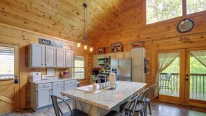 A kitchen with a central island, bar stools, wooden cabinets, and a sign reading "LAKE HOUSE". - Lakefront Cabin in the Smoky Mountains (Sevierville)