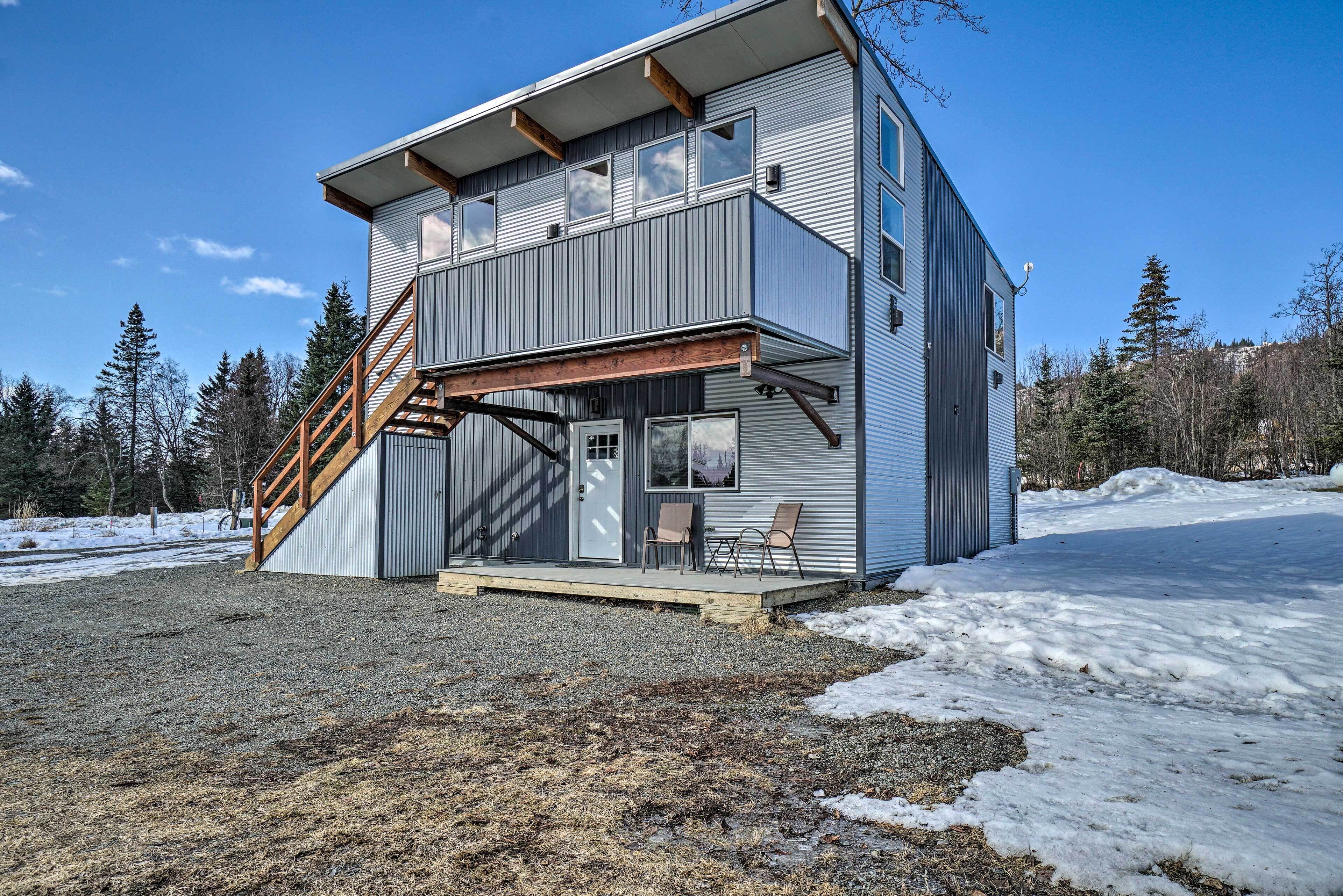 A two-story building with a balcony, a wooden staircase, and a covered porch area.