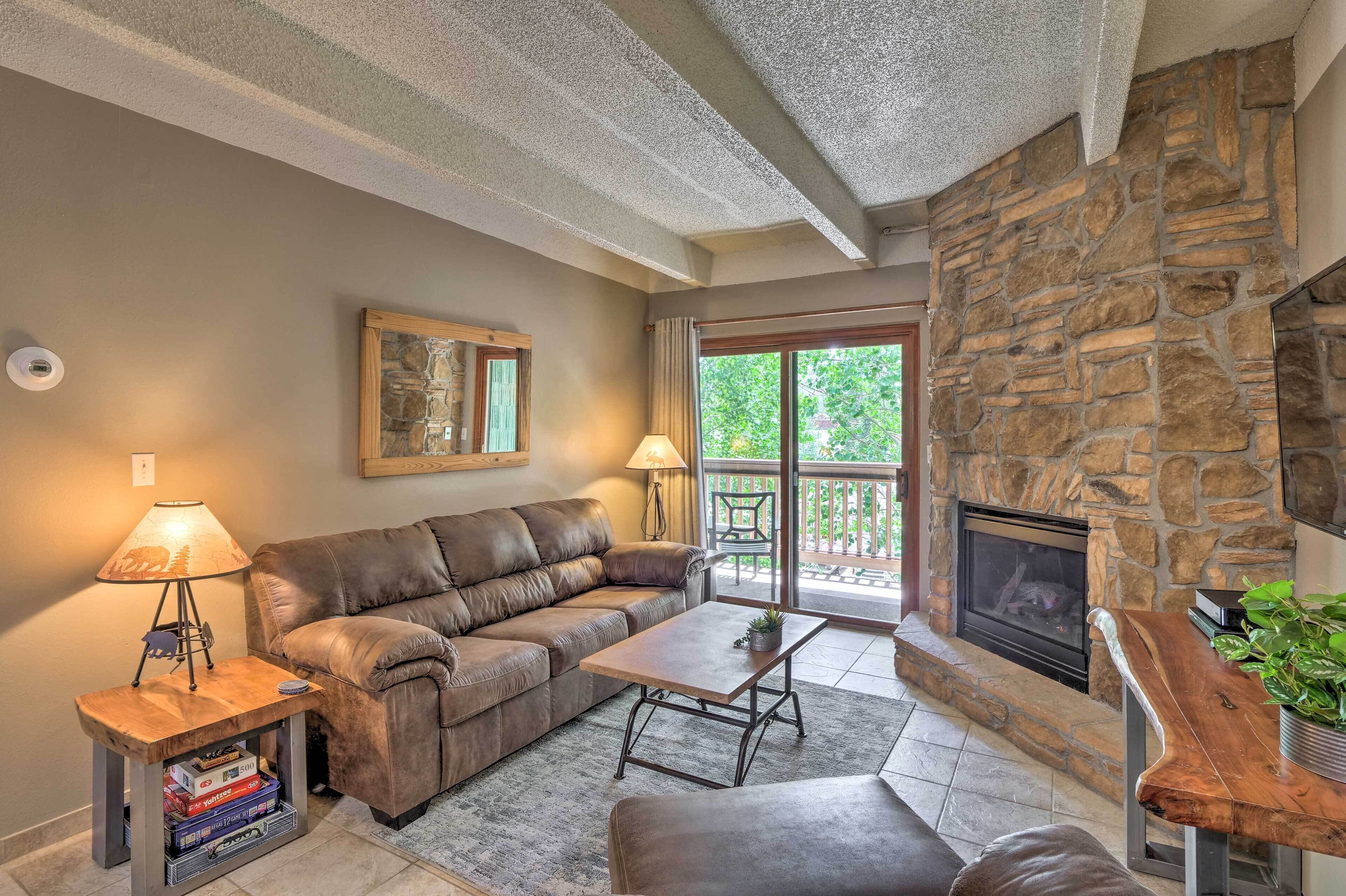 A living room with a stone fireplace, leather sofa, and a coffee table.