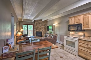 A cozy kitchen with a stone fireplace, wooden cabinets, and a dining area with a table and chairs. - Frisco Condo 2 Blocks to Main St: Year-round Fun! (Frisco)