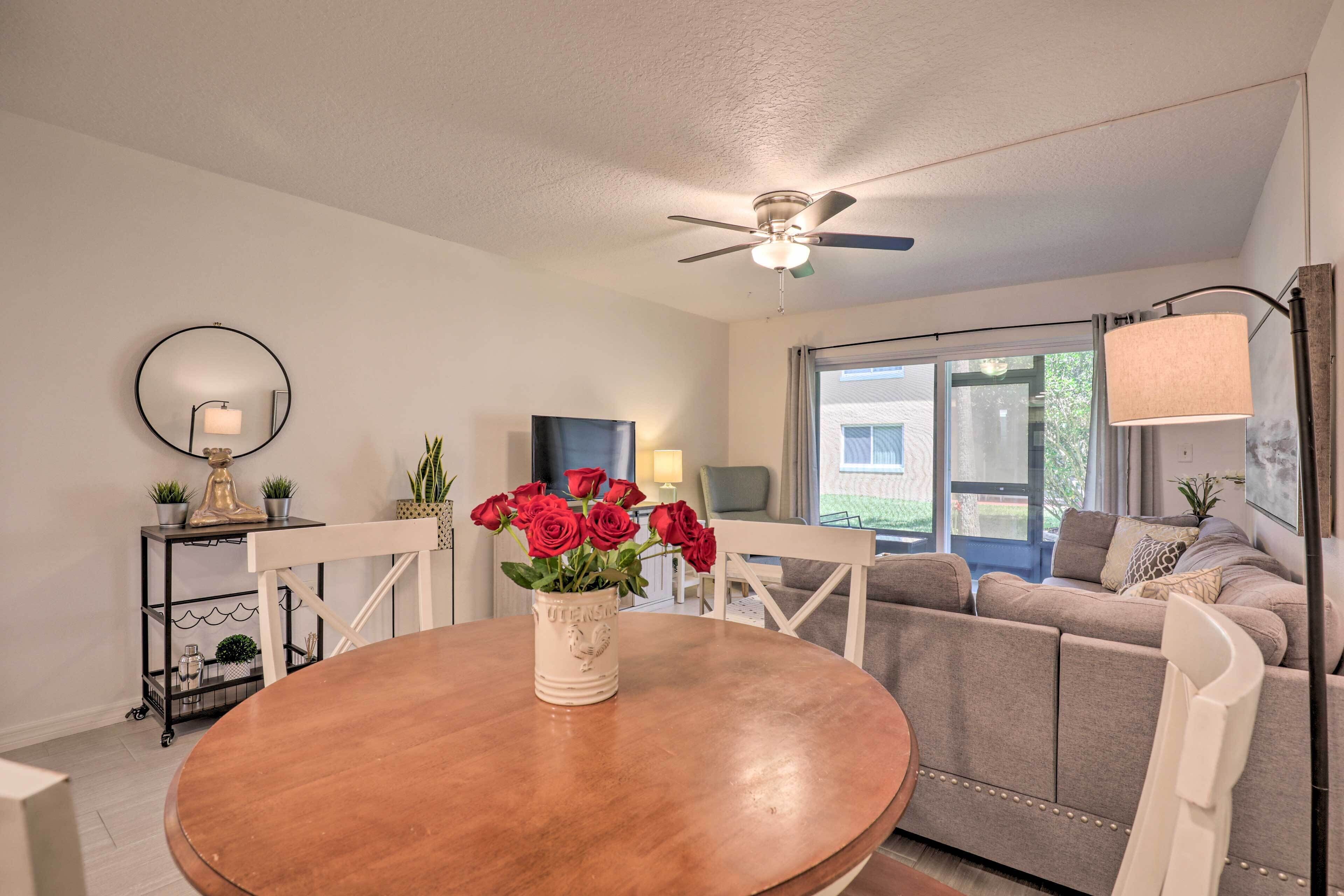 A modern living room with a round wooden table, a ceiling fan, a sofa, and a TV.