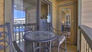 A glass-enclosed balcony with a round table and metal chairs, a sliding glass door, and a view of a snowy landscape. - Cozy Ski-in/ski-out Granby Condo w/ Balcony! (Granby)