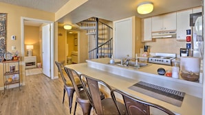 A kitchen with a central island, chairs, a stove, and a staircase leading to another room. - Cozy Ski-in/ski-out Granby Condo w/ Balcony! (Granby)
