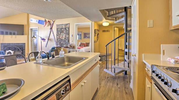 A kitchen with a large island, a stove, and a dining area with chairs and a table. - Cozy Ski-in/ski-out Granby Condo w/ Balcony! (Granby)