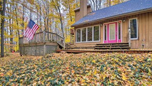 A wooden cabin with a pink door, a deck, and an American flag. - Family Escape - Near Little Traverse Wheelway (Harbor Springs)