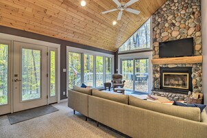 A spacious living room with a stone fireplace, a large sofa, and a ceiling fan.