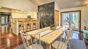 A spacious kitchen with wooden cabinets, a central island, and a dining area with a large table and chairs. - Family Escape - Near Little Traverse Wheelway (Harbor Springs)