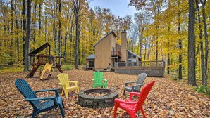 A cabin with a deck, surrounded by autumn leaves, and a fire pit with chairs. - Family Escape - Near Little Traverse Wheelway (Harbor Springs)