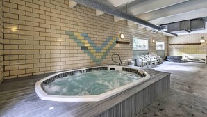 Un espace bien-être comprenant un jacuzzi, une terrasse en bois et un coin salon.