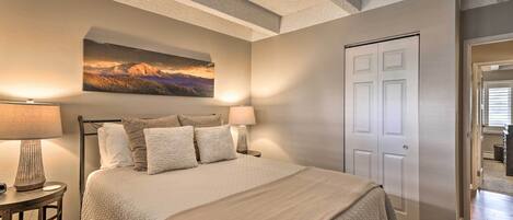 A bedroom with a bed, two bedside tables with lamps, a door, and a painting on the wall.