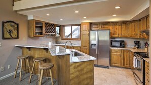 A kitchen with wooden cabinets, a stainless steel refrigerator, a microwave, and a granite countertop. - Half-mi to Copper Mtn Slopes: Frisco Unit w/ Loft (Frisco)