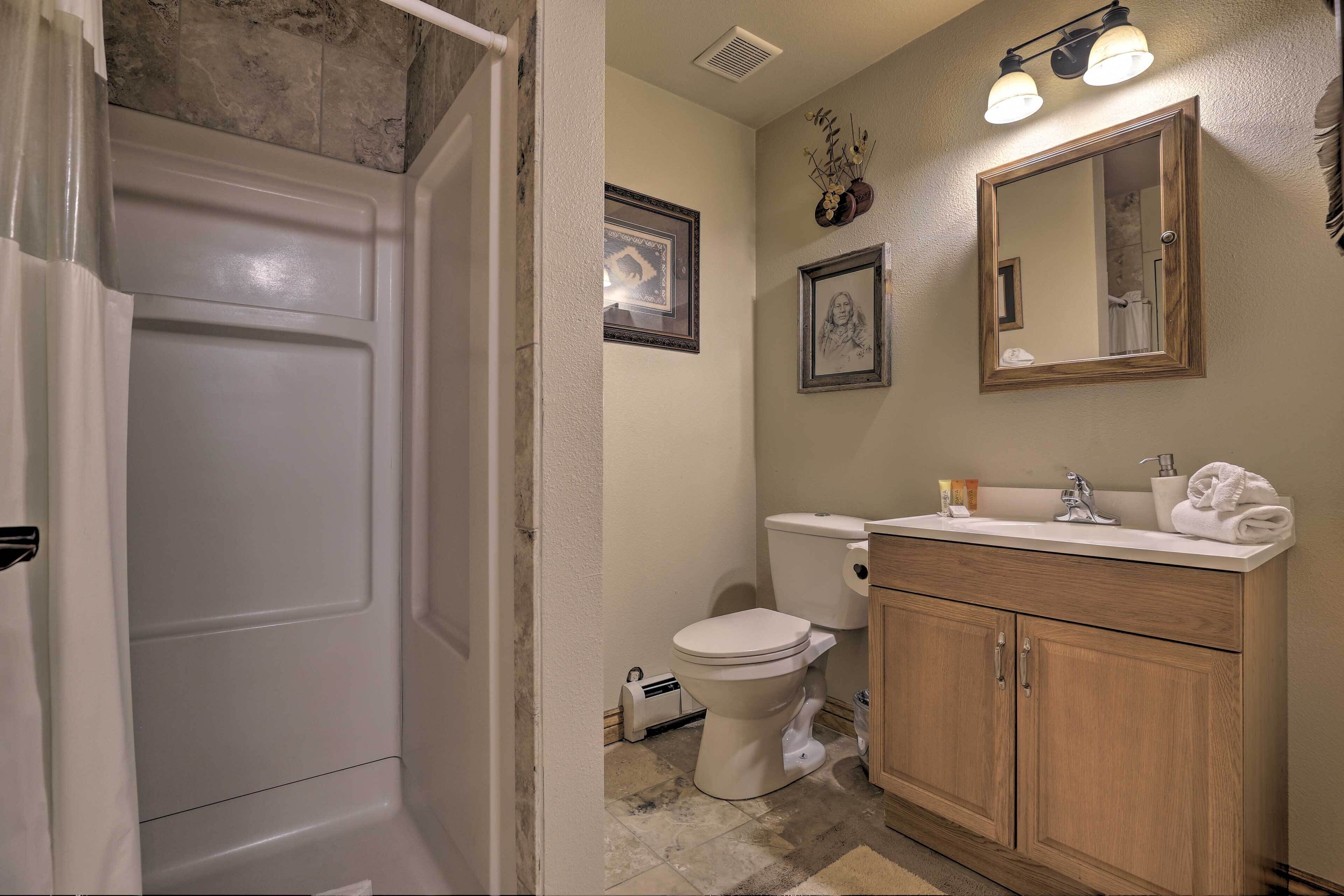 A bathroom with a toilet, sink, vanity, and a shower area.