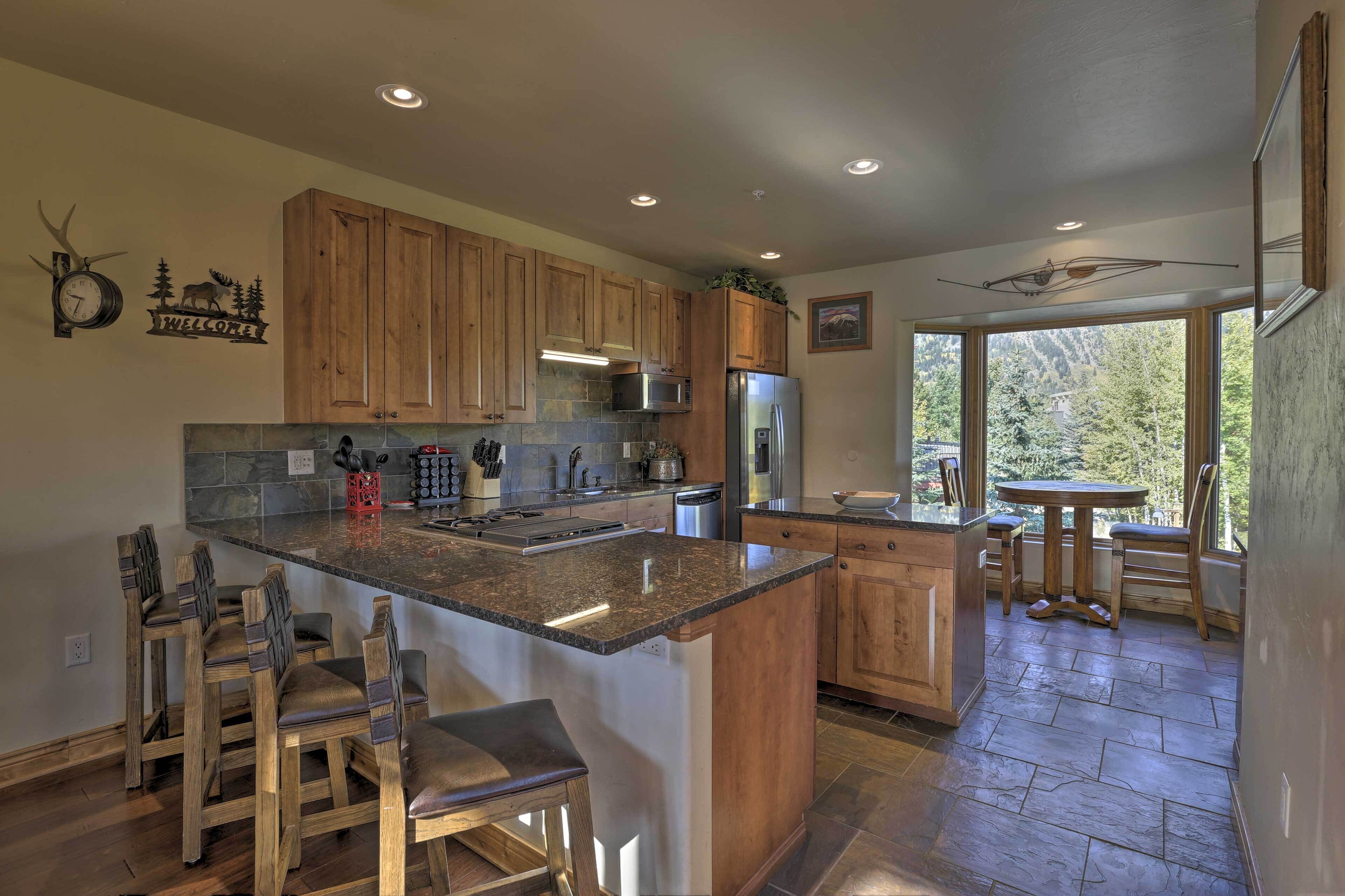 A kitchen with wooden cabinets, a granite countertop, and a built-in island with bar stools.