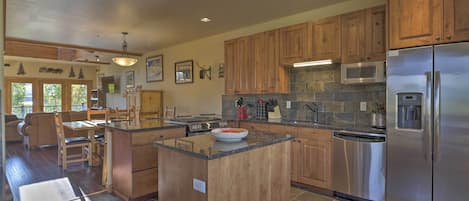 Una cocina moderna con armarios de madera, una isla central, electrodomésticos de acero inoxidable y un comedor con vistas.