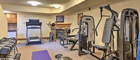 A gym with exercise equipment, a bench, dumbbells, and a treadmill.