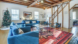 A spacious living room with a wooden ceiling, a Christmas tree, blue sofas, and a staircase leading to another level. - Deck & Fire Pit: Cottage Near Monadnock State Park (Jaffrey)