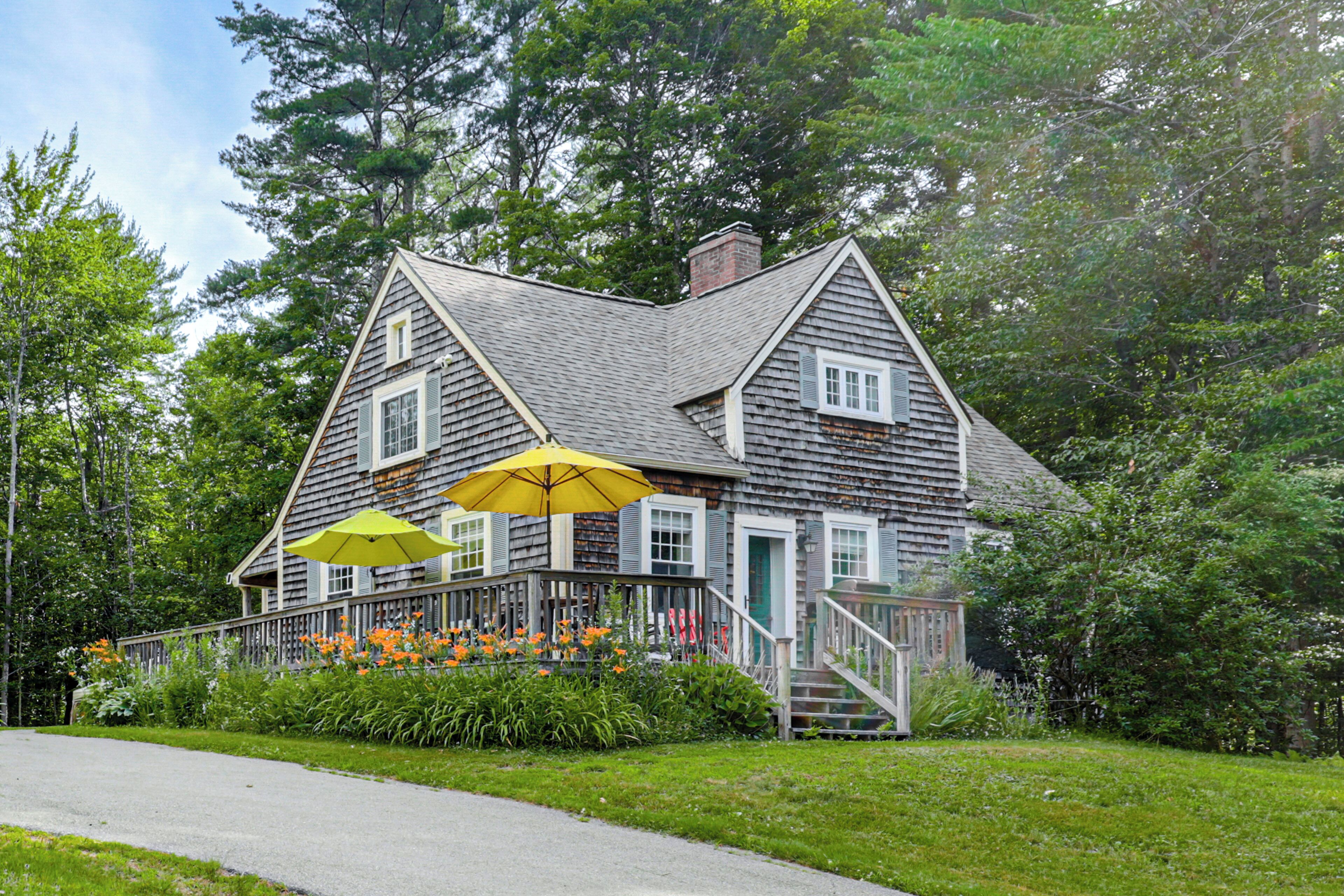 A wooden house with a porch, a staircase, and a yellow umbrella.