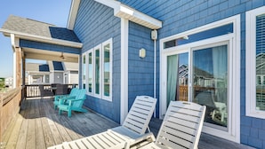 Una casa blu con veranda in legno, finestre con cornice bianca e una porta scorrevole in vetro.