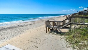 Una spiaggia con una passerella di legno che conduce a un edificio con una bandiera.
