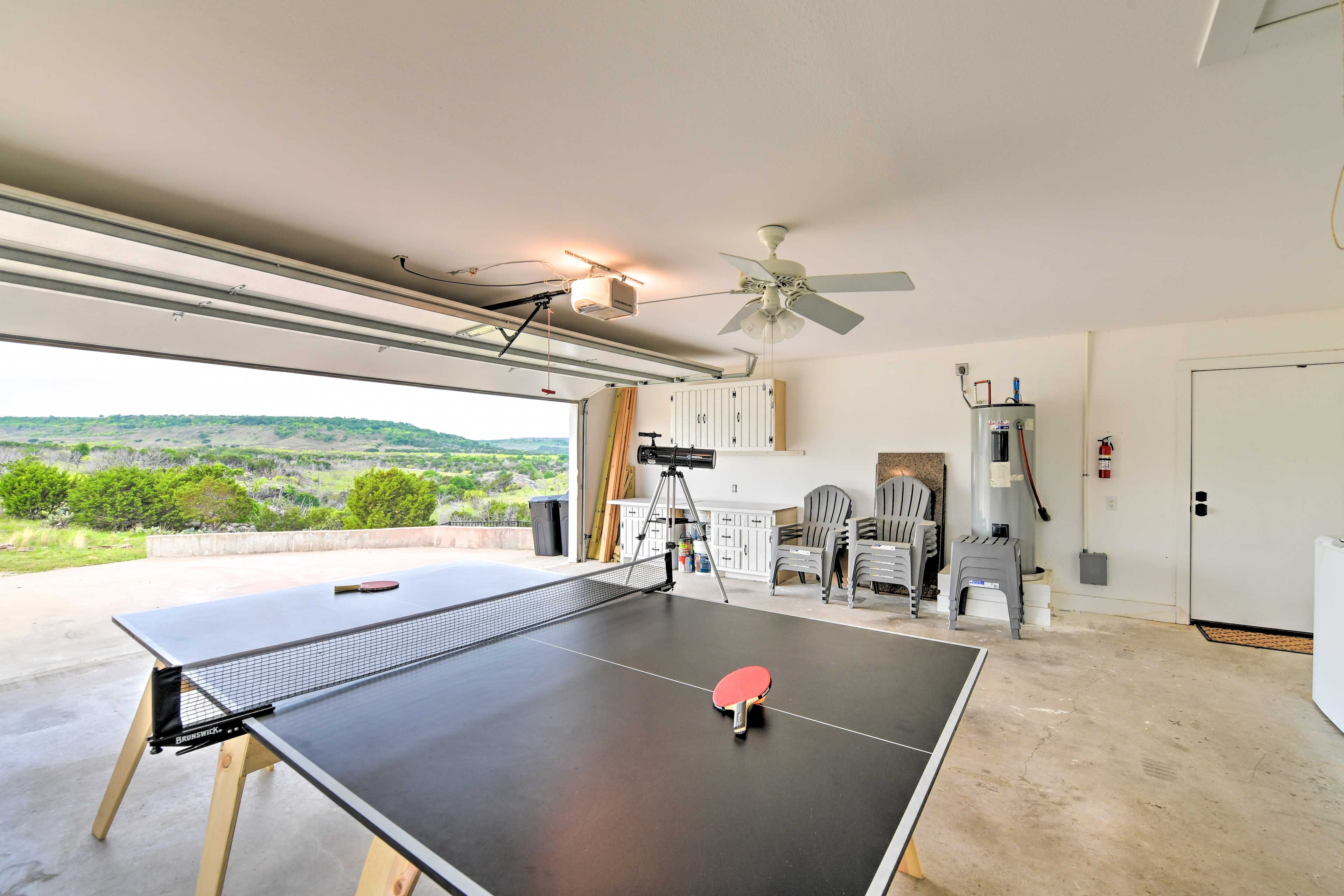 Un tavolo da ping pong in una stanza con vista su un paesaggio verde.