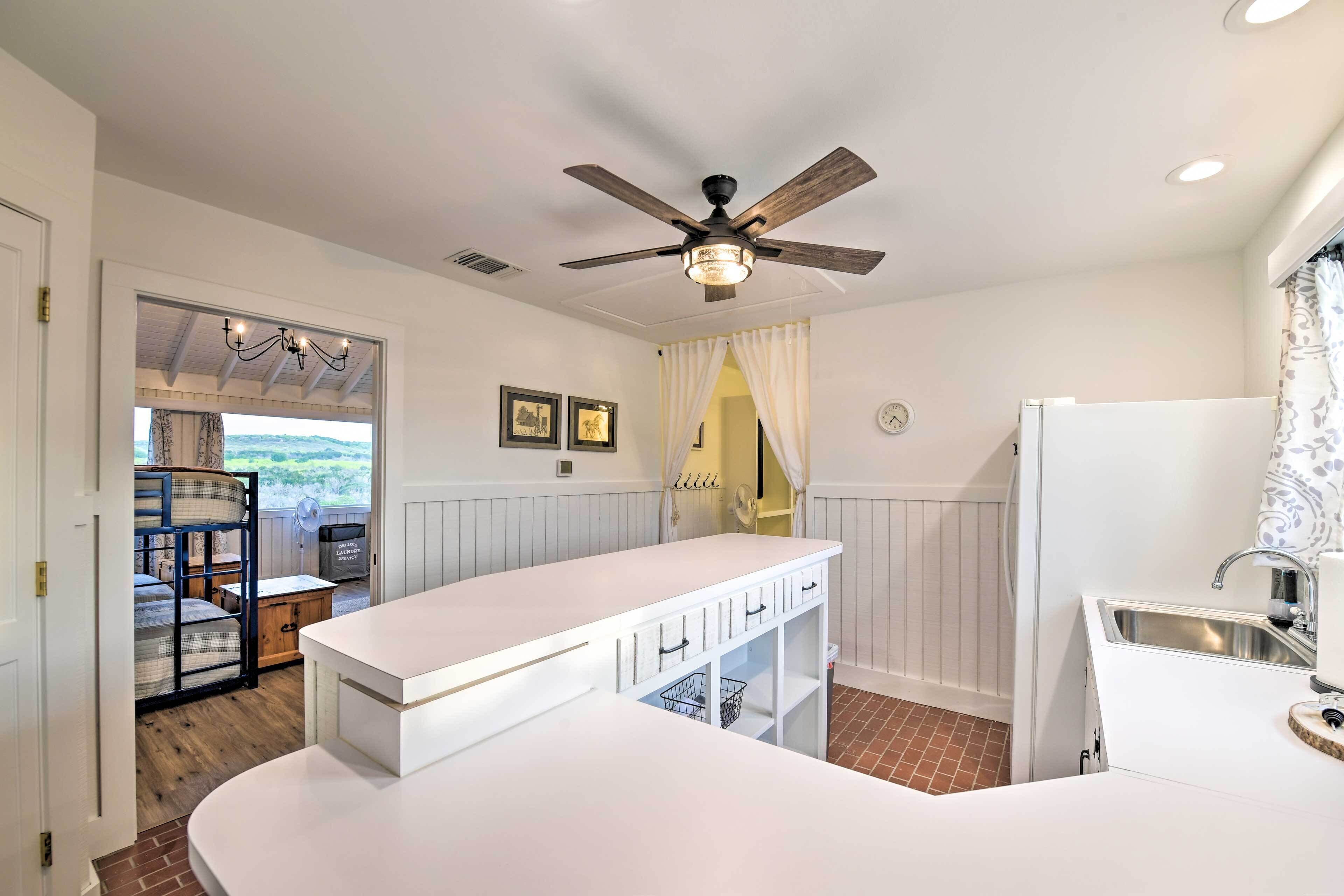 A modern kitchen with white cabinetry, a built-in sink, and a ceiling fan.