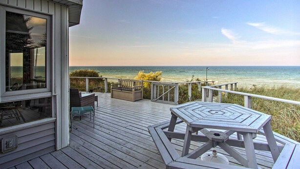 A wooden deck with a table and chairs, overlooking a beach. - Lakefront Montague Cottage w/ Deck & Beach! (Montague)