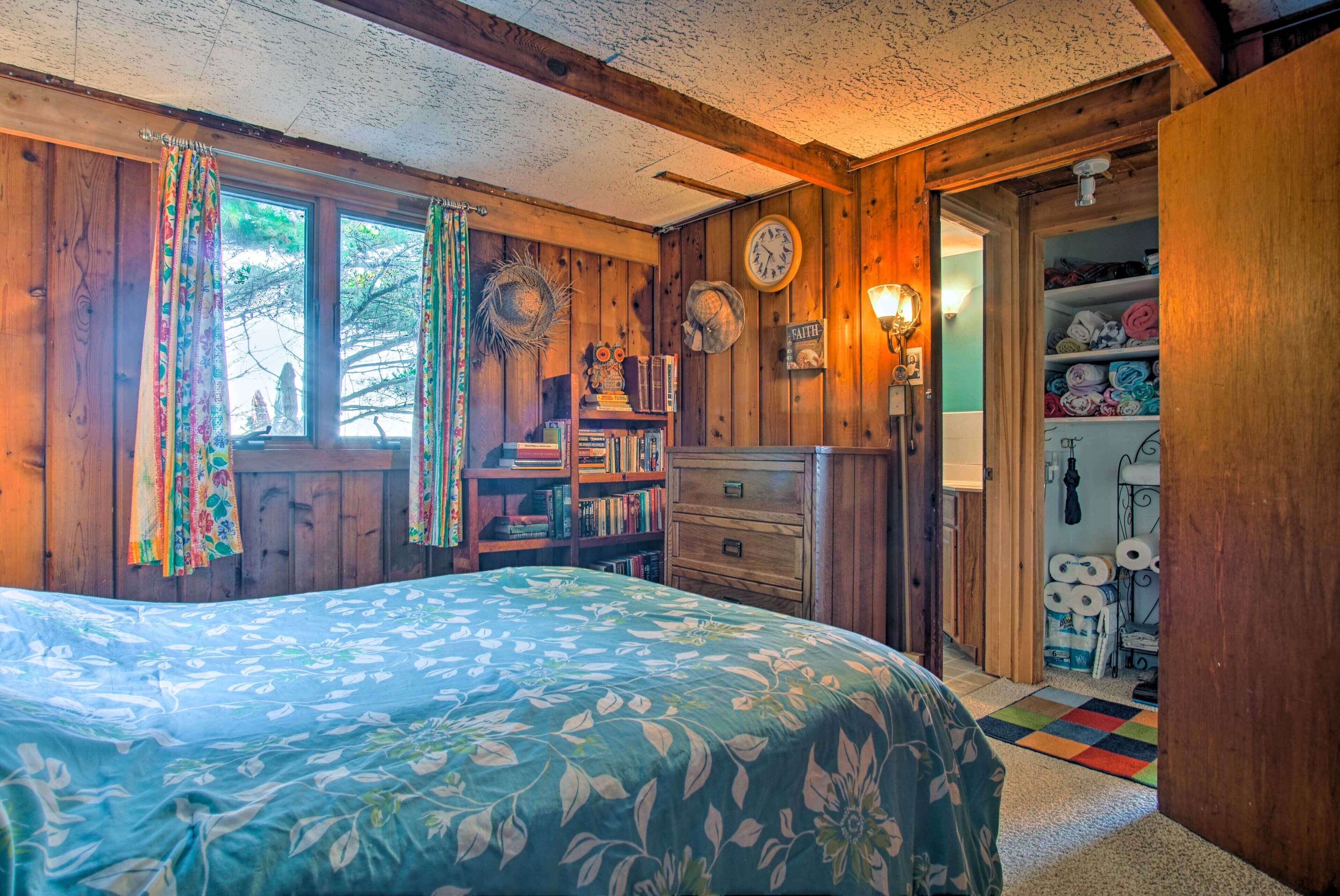 Een gezellige kamer met een bed, houten wanden, een boekenplank en een deur naar een badkamer.