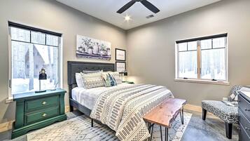 A bedroom with a bed, a desk, a dresser, and two windows.