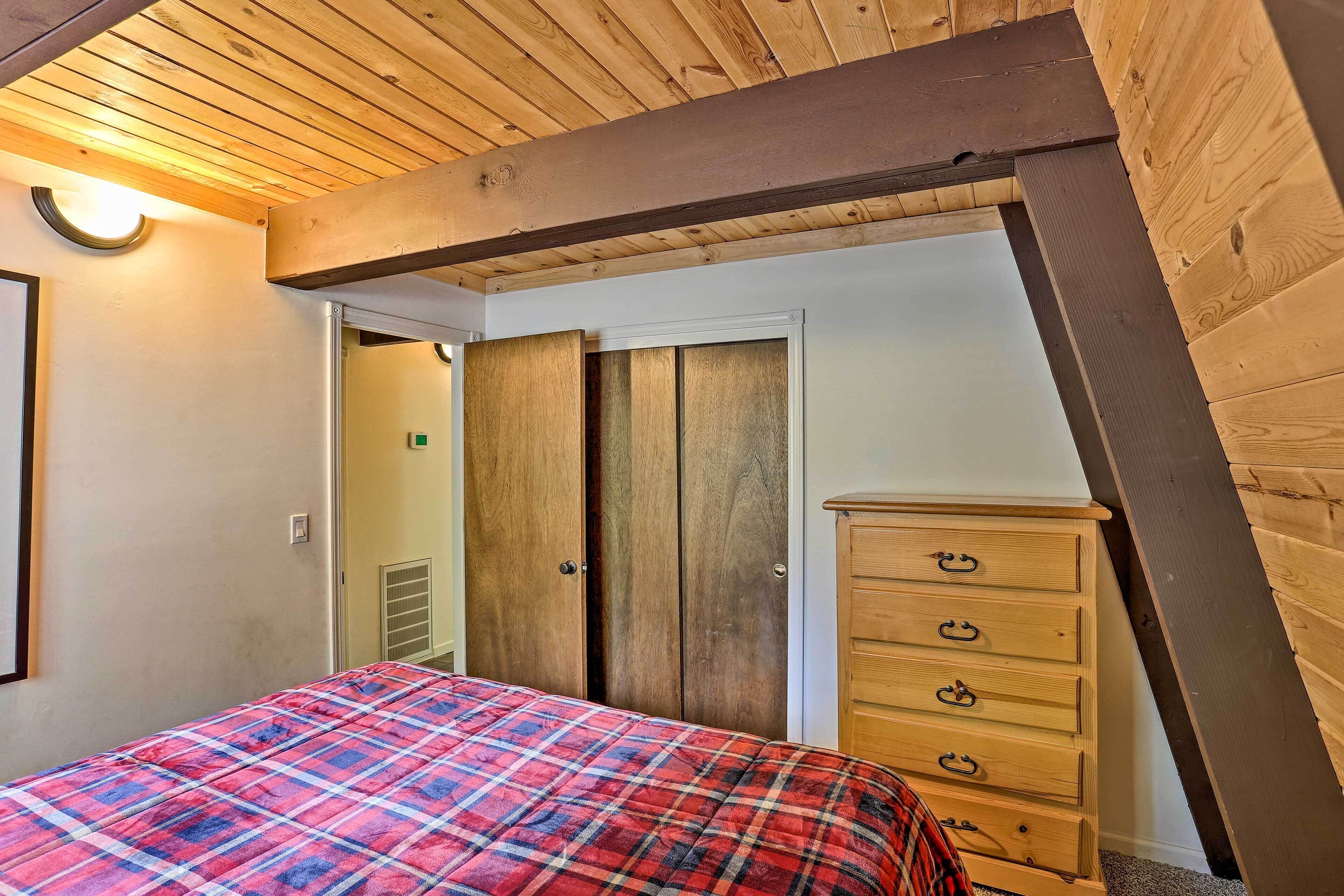 A bedroom with a bed, wooden wardrobe, and a dresser.