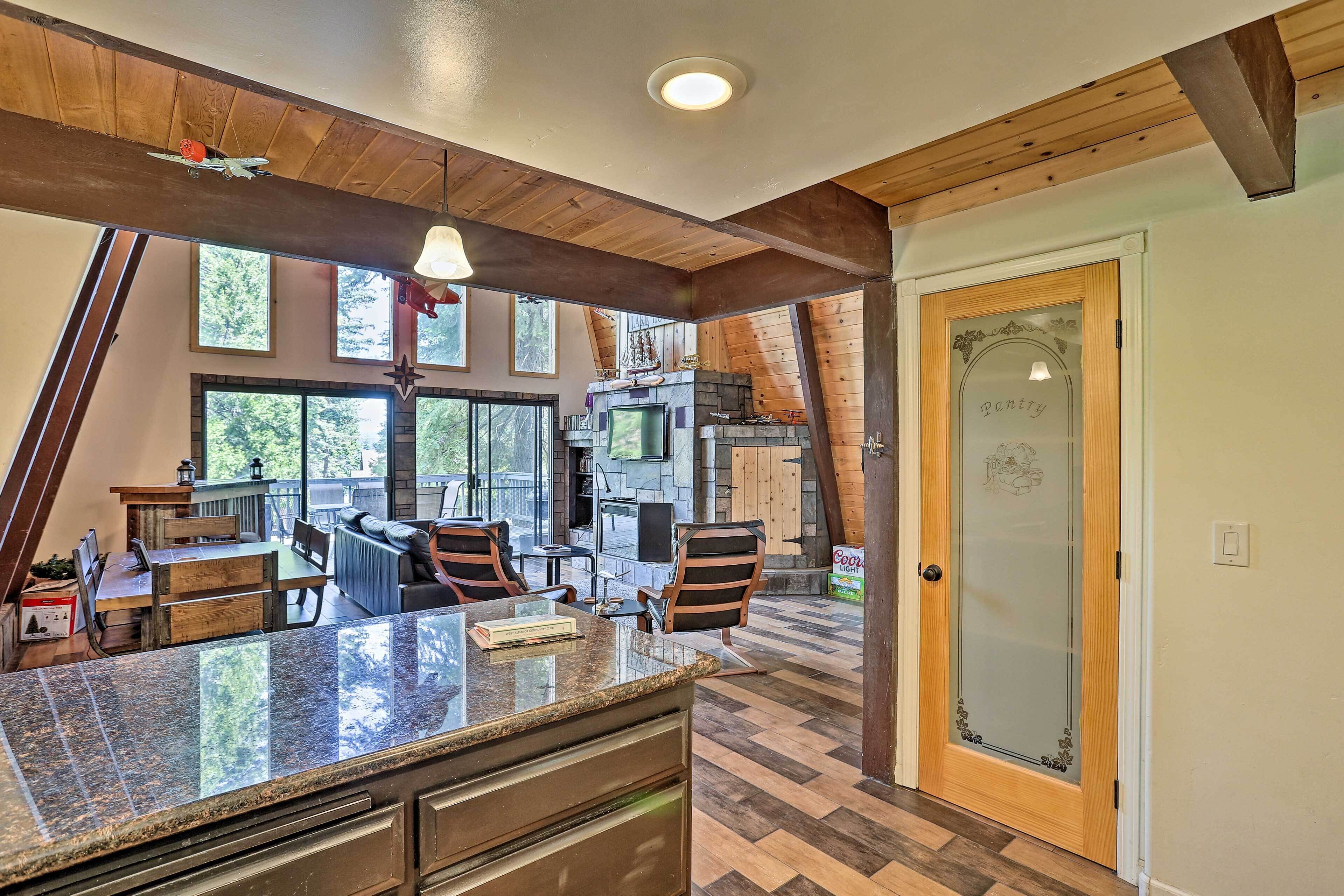 A kitchen with a granite countertop, wooden ceiling beams, and a view of the outdoors.