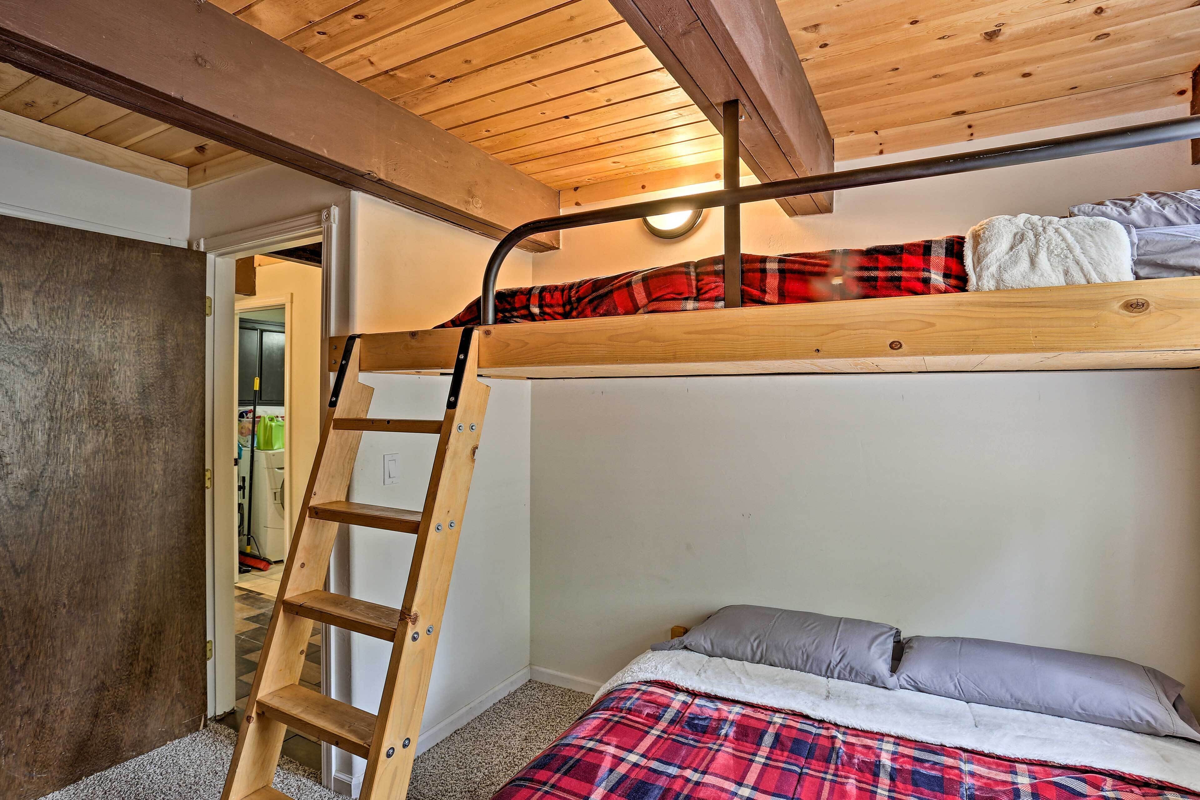 A bunk bed with a wooden ladder, a plaid blanket, and a gray pillow.