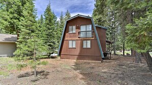 Une cabane à deux étages, dotée d’un toit en pente, entourée d’une forêt dense.