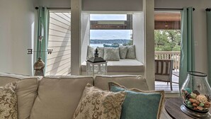 Ein gemütliches Wohnzimmer mit einer Couch, einem Glastisch mit Dekoration und Blick ins Freie durch ein Fenster.