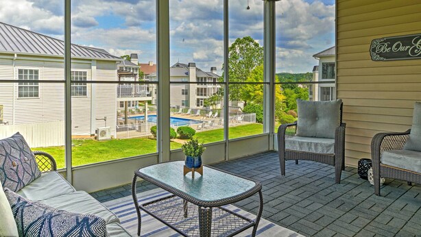 A covered patio with wicker furniture, a glass table, and a view of a backyard with a pool. - Branson Condo: Pool Access, Near Table Rock Lake! (Branson)