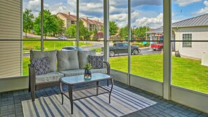 A covered porch with wicker furniture, a glass table, and a view of a residential street. - Branson Condo: Pool Access, Near Table Rock Lake! (Branson)