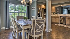 A dining area with a wooden table and chairs, a chandelier, and a view of the outdoors through large windows. - Branson Condo: Pool Access, Near Table Rock Lake! (Branson)