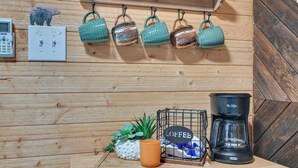 A wooden wall with a light switch, a coffee maker, and a small plant. - Tiny Home w/ Hot Tub & Mini Highland Cows! (Loudonville)