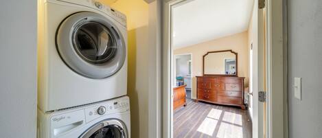 Una sala de lavandería con dos lavadoras apiladas y un aparador de madera en la habitación contigua.